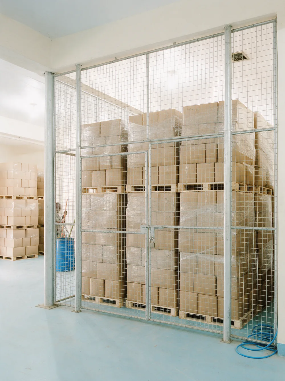 Cartons stacked behind the steel mesh of a locked store cage.