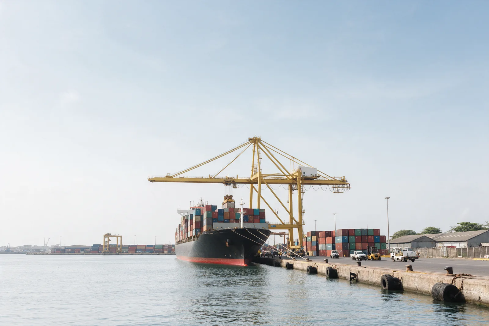 A container ship being worked by quay cranes.
