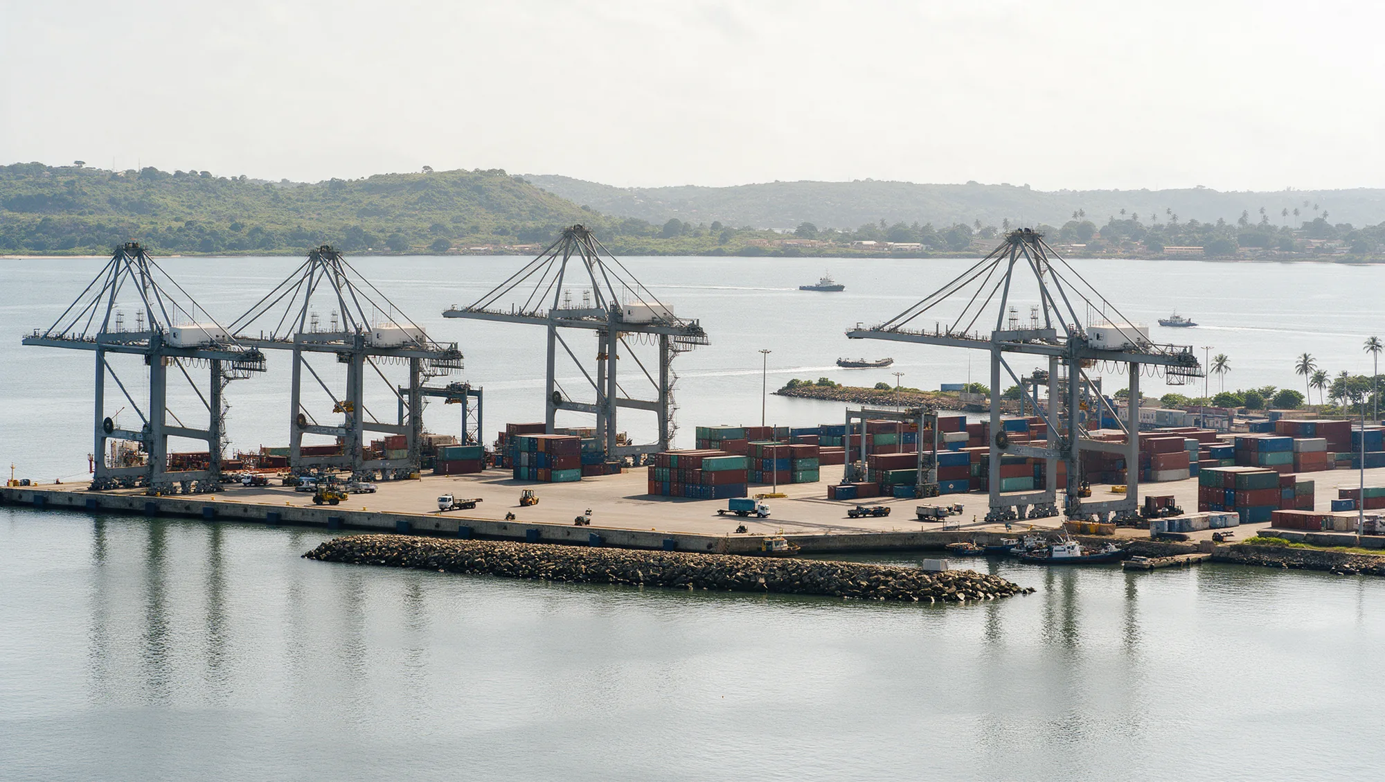A wide view of a container port with gantry cranes and container stacks.
